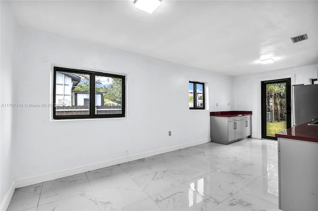 spare room with marble finish floor, baseboards, and visible vents