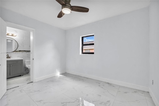 unfurnished bedroom featuring marble finish floor, baseboards, and ensuite bathroom