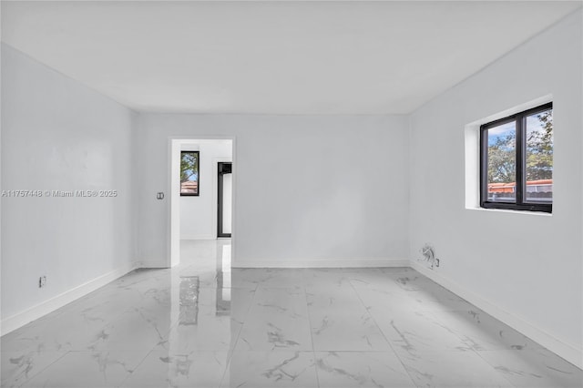 unfurnished room with marble finish floor and baseboards