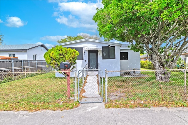 view of front of property featuring a fenced front yard, a gate, and a front lawn