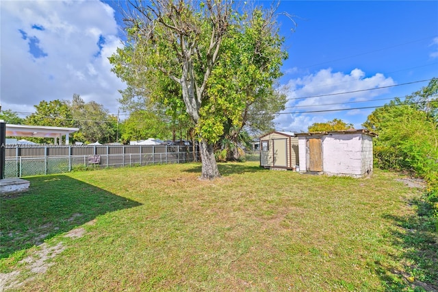 view of yard featuring fence, a storage unit, and an outbuilding