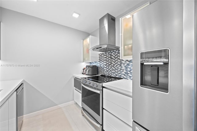 kitchen with tasteful backsplash, wall chimney exhaust hood, stainless steel appliances, light countertops, and white cabinetry