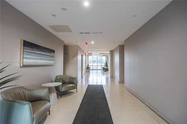 hall with floor to ceiling windows and light tile patterned flooring