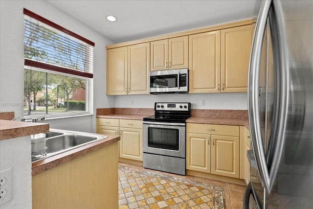 kitchen with recessed lighting, appliances with stainless steel finishes, light brown cabinets, a sink, and light tile patterned flooring