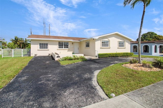 single story home featuring a front yard, fence, aphalt driveway, and stucco siding