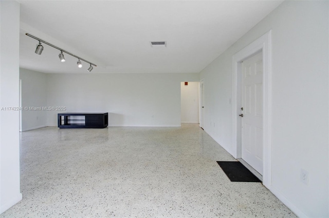 unfurnished living room featuring visible vents, track lighting, and speckled floor