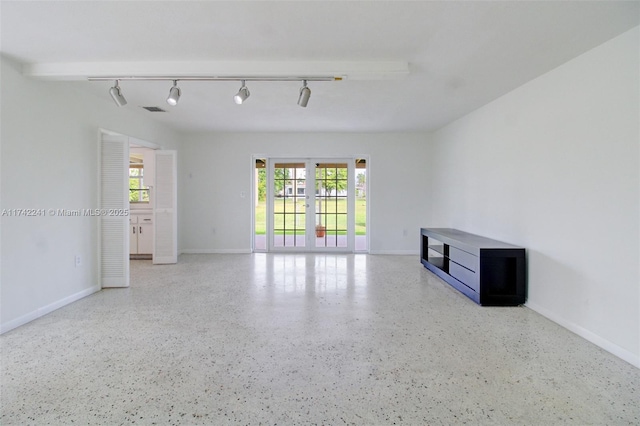 empty room featuring rail lighting, visible vents, baseboards, and speckled floor