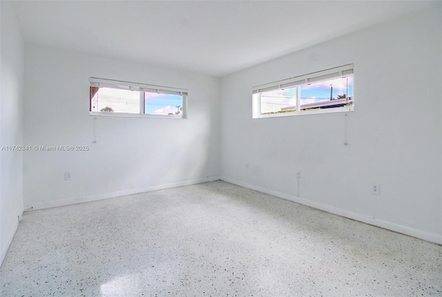 spare room featuring baseboards and speckled floor