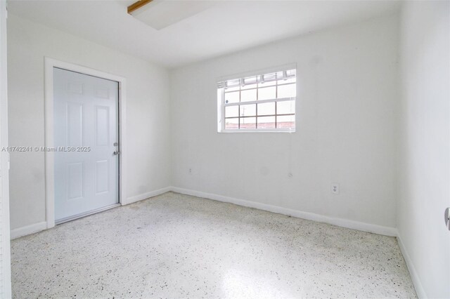 spare room with speckled floor and baseboards