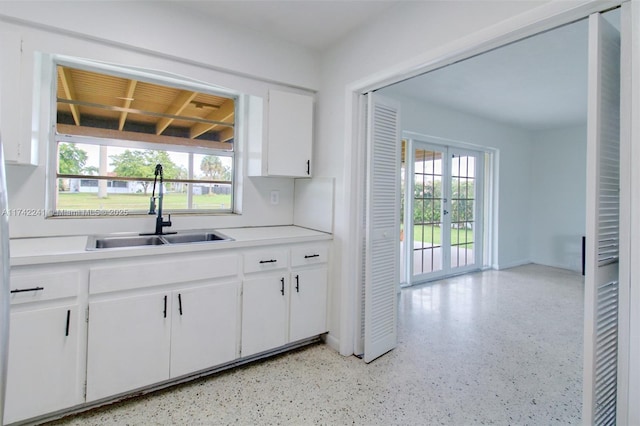 kitchen with a wealth of natural light, white cabinetry, light countertops, and a sink