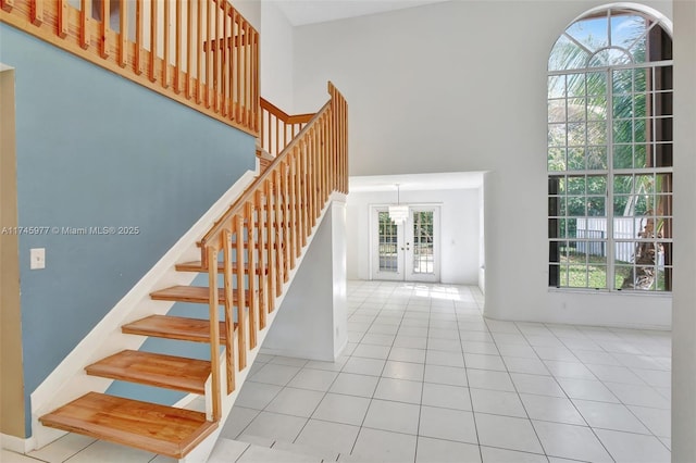 stairs with french doors, a high ceiling, and tile patterned floors