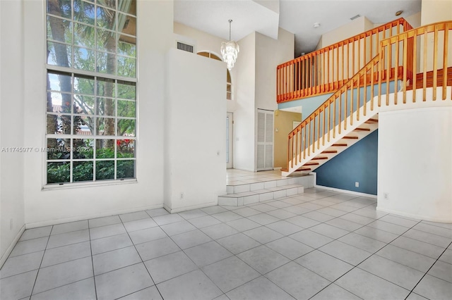 spare room featuring a notable chandelier, a high ceiling, visible vents, stairway, and tile patterned floors