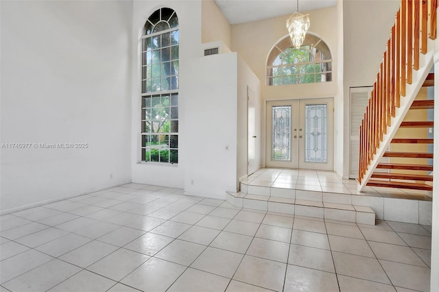 foyer with tile patterned flooring, french doors, visible vents, and a notable chandelier