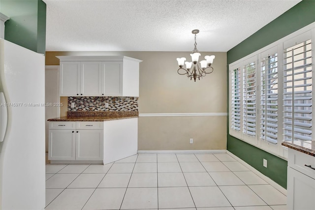 kitchen featuring pendant lighting, backsplash, white cabinets, and a notable chandelier