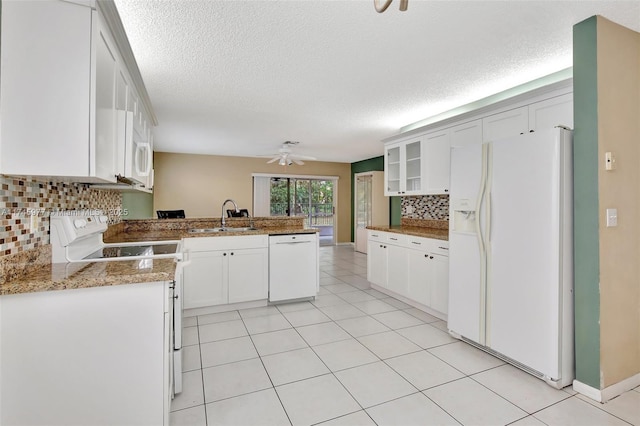 kitchen featuring white appliances, light tile patterned floors, a peninsula, white cabinetry, and a sink