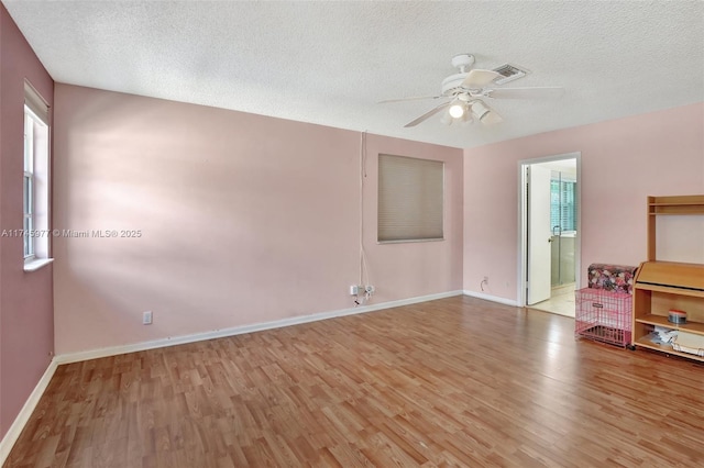 unfurnished room featuring a textured ceiling, wood finished floors, a ceiling fan, and baseboards