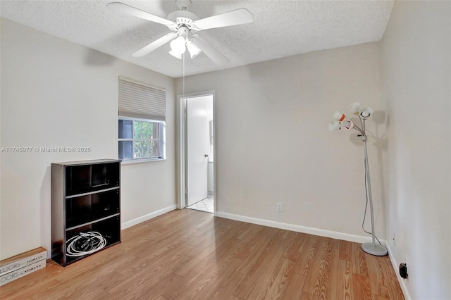 spare room with a ceiling fan, a textured ceiling, baseboards, and wood finished floors