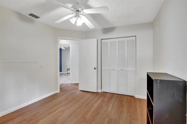 unfurnished bedroom with light wood-style flooring, a textured ceiling, visible vents, and baseboards