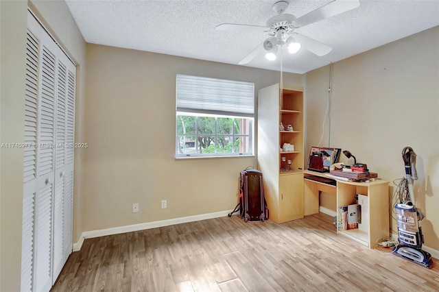 office area with a textured ceiling, light wood-type flooring, and baseboards