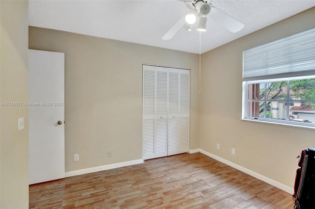 unfurnished bedroom with a textured ceiling, a closet, baseboards, and wood finished floors