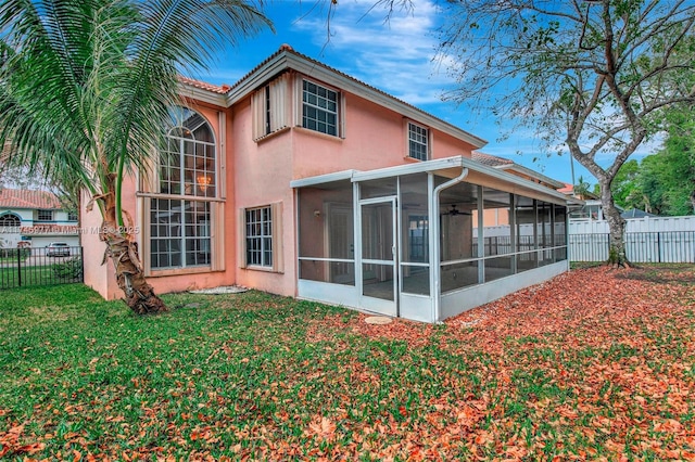 rear view of house featuring a sunroom, a fenced backyard, a yard, and stucco siding