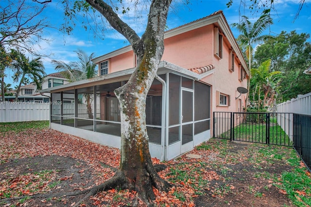 back of property with a sunroom, a fenced backyard, and stucco siding