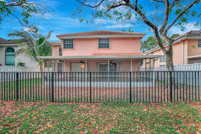 view of front of house featuring ceiling fan, a fenced backyard, a tile roof, stucco siding, and a patio area