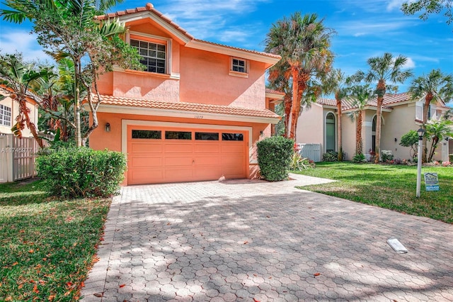 mediterranean / spanish home with stucco siding, a tile roof, an attached garage, decorative driveway, and a front yard