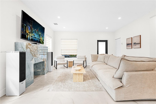 living room with marble finish floor, a premium fireplace, visible vents, and recessed lighting