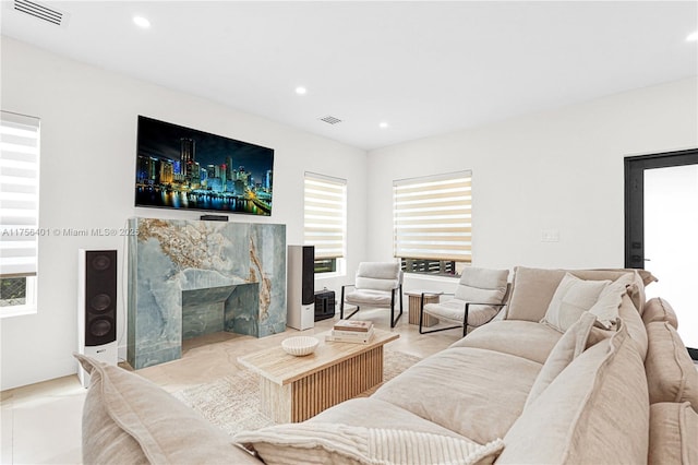 living area with recessed lighting, a healthy amount of sunlight, visible vents, and a premium fireplace