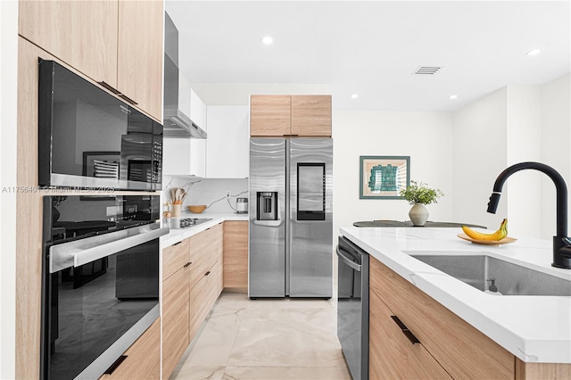 kitchen featuring light brown cabinets, stainless steel appliances, modern cabinets, and a sink