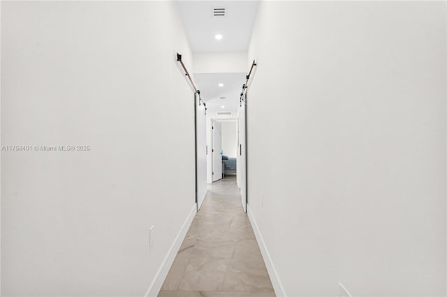 corridor featuring recessed lighting, visible vents, baseboards, and a barn door