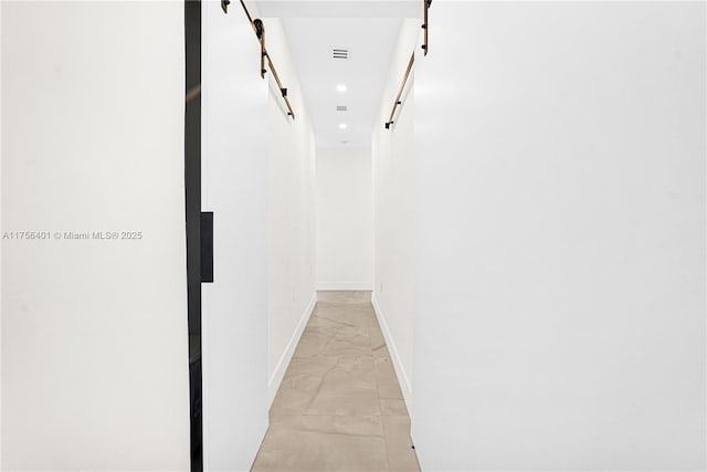 corridor with recessed lighting, marble finish floor, baseboards, and a barn door