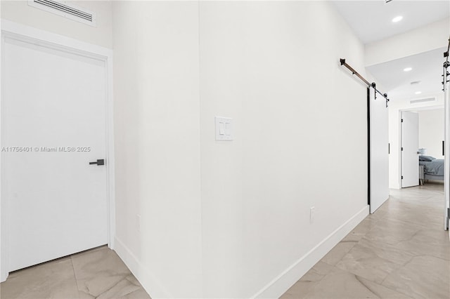 hall featuring a barn door, visible vents, baseboards, and recessed lighting