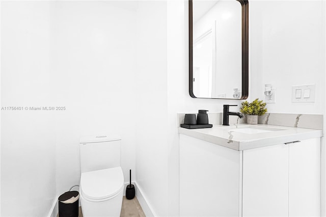 bathroom with toilet, baseboards, and vanity