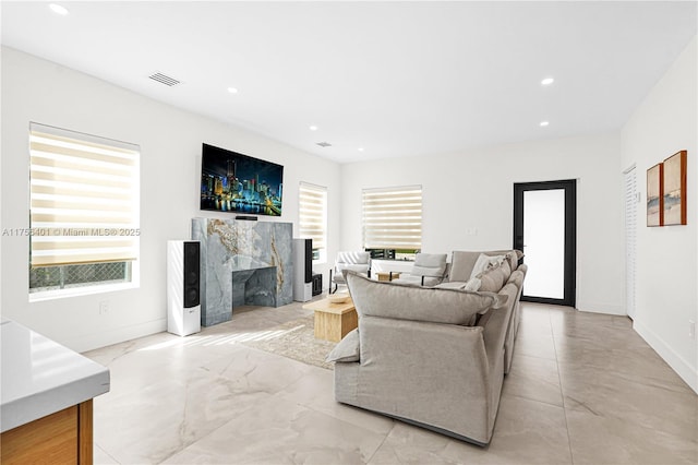 living area featuring recessed lighting, visible vents, baseboards, and a high end fireplace