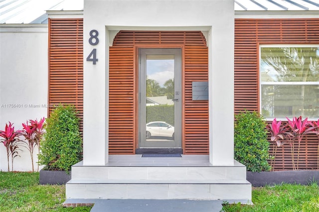 view of exterior entry featuring a standing seam roof and stucco siding