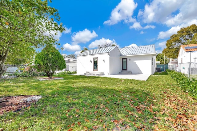 back of property with a lawn, a fenced backyard, metal roof, a standing seam roof, and stucco siding