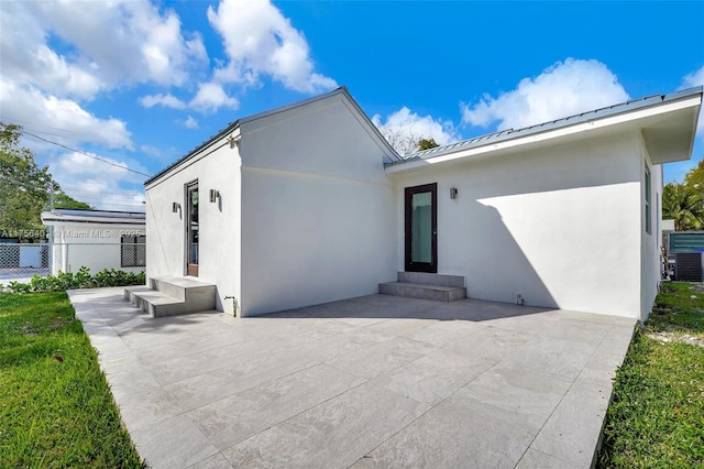 view of front of property with metal roof, a patio, fence, stucco siding, and a standing seam roof