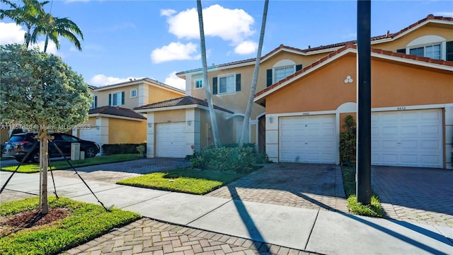 view of front of house featuring a garage, decorative driveway, and stucco siding