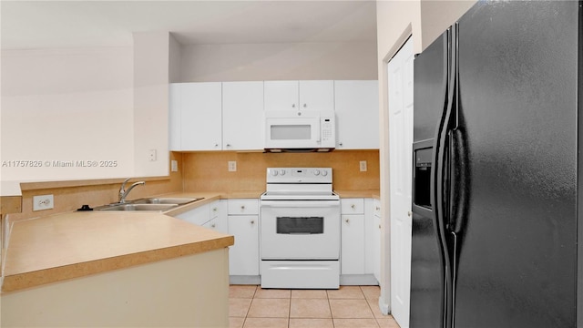 kitchen with light tile patterned floors, white appliances, a sink, white cabinets, and light countertops