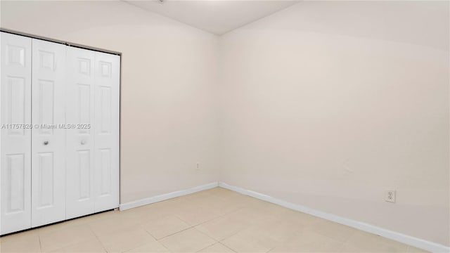 unfurnished bedroom with a closet, baseboards, and light tile patterned floors