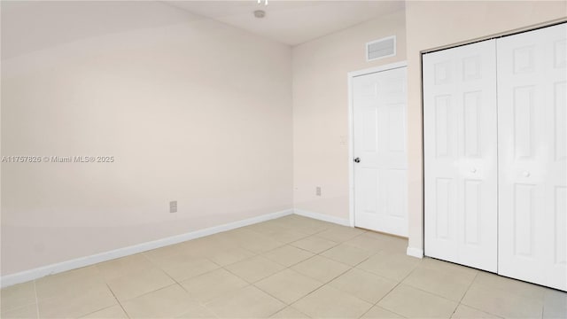 unfurnished bedroom featuring light tile patterned floors, a closet, visible vents, and baseboards