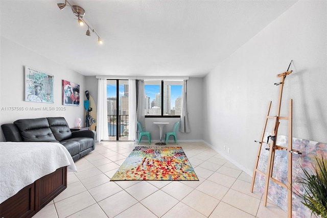 living area featuring light tile patterned floors, baseboards, rail lighting, a view of city, and floor to ceiling windows