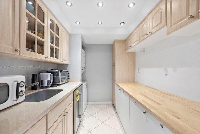 kitchen with light tile patterned floors, white microwave, recessed lighting, light brown cabinetry, and glass insert cabinets