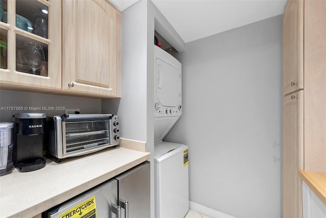 laundry area featuring stacked washer and clothes dryer, cabinet space, and a toaster