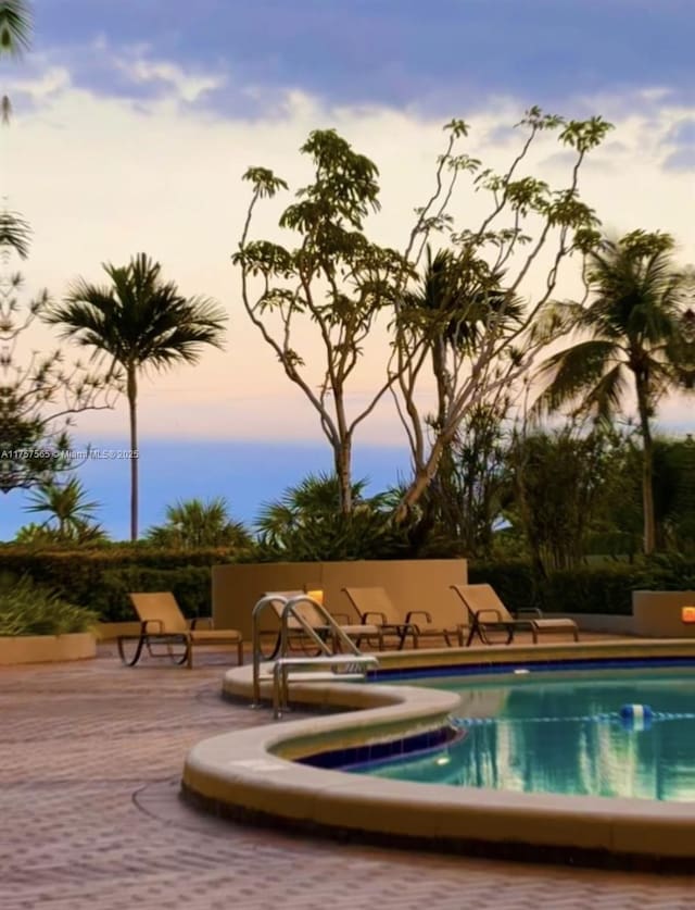 pool at dusk featuring a patio