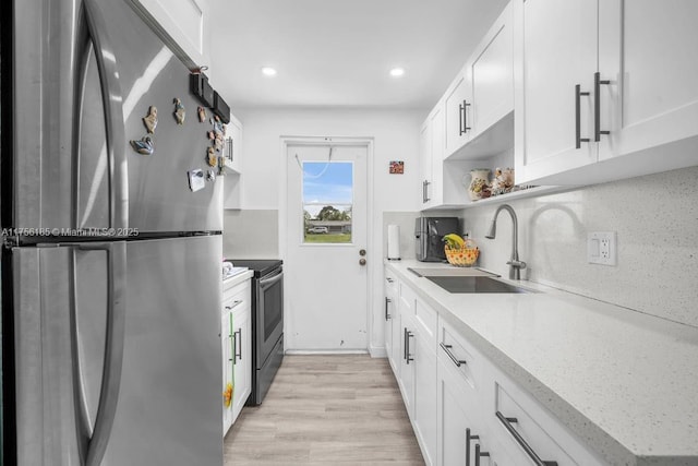 kitchen with decorative backsplash, appliances with stainless steel finishes, light wood-style floors, white cabinetry, and a sink