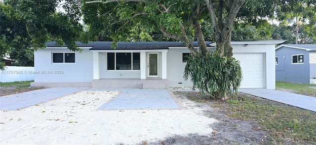 ranch-style home featuring concrete driveway, an attached garage, and stucco siding