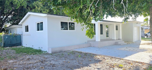 view of front facade featuring a porch, an attached garage, and stucco siding